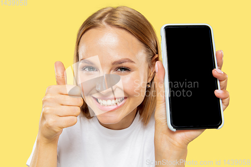 Image of Caucasian young woman\'s half-length portrait on yellow background