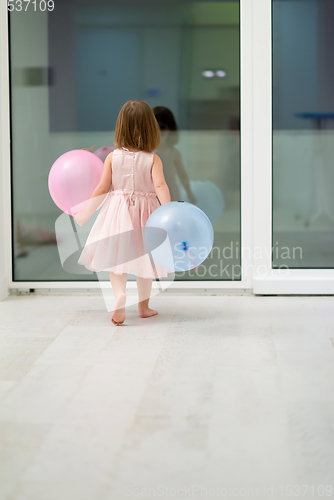 Image of cute little girl playing with balloons