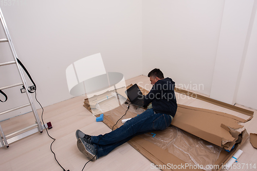 Image of man using laptop while lying on cardboard box