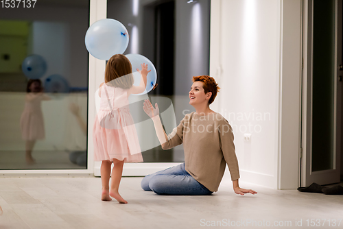 Image of mother and cute little daughter playing with balloons