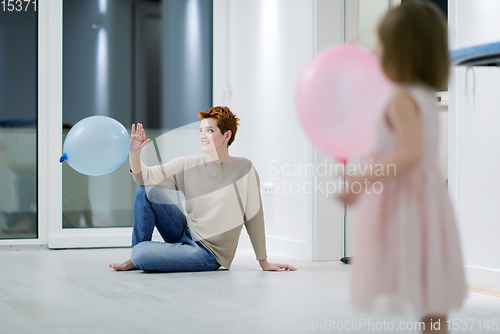 Image of mother and cute little daughter playing with balloons