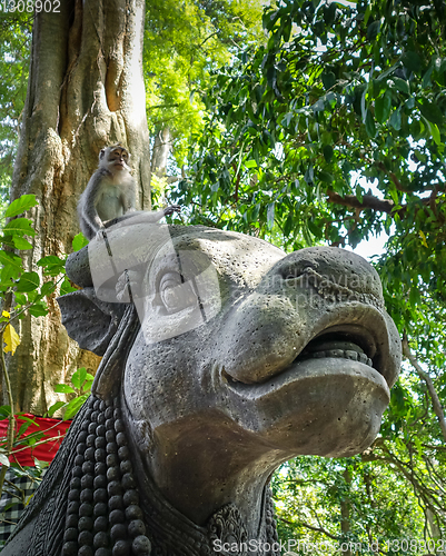 Image of Monkey on a cow statue in the Monkey Forest, Ubud, Bali, Indones