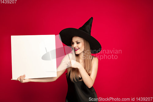 Image of Young woman in hat as a witch on red background