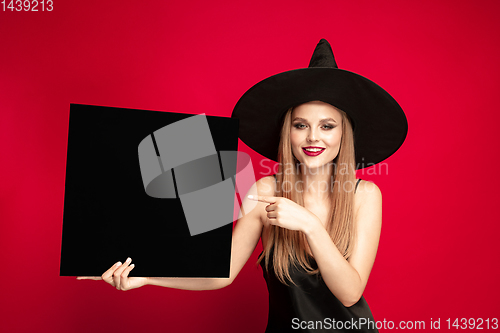 Image of Young woman in hat as a witch on red background