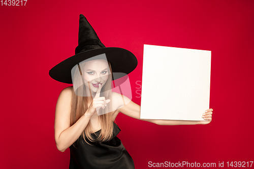 Image of Young woman in hat as a witch on red background