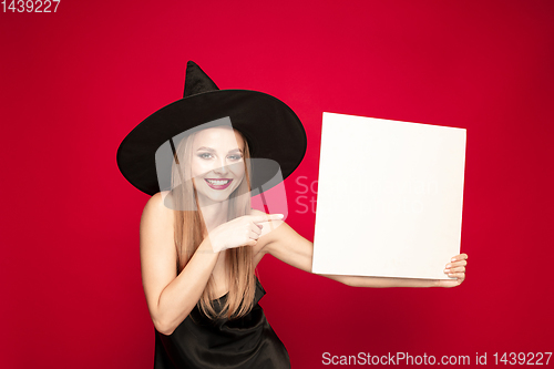 Image of Young woman in hat as a witch on red background