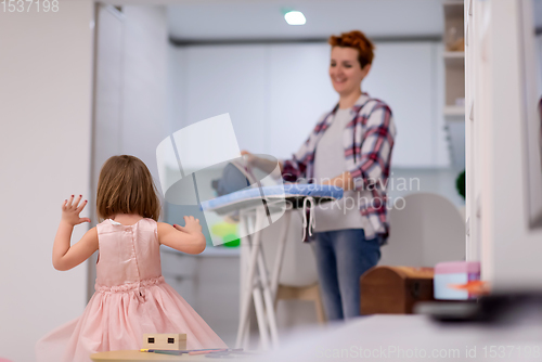 Image of mother and little daughter spending time together at home