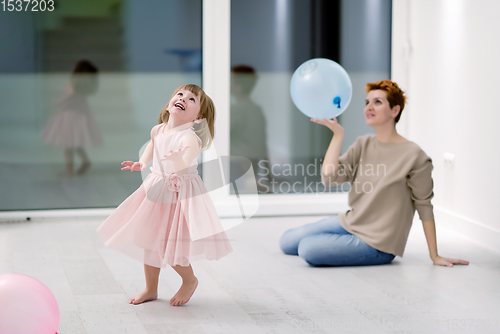 Image of mother and cute little daughter playing with balloons