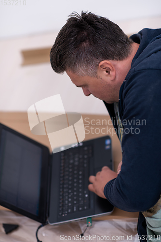 Image of man using laptop while lying on cardboard box