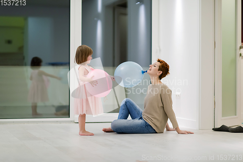 Image of mother and cute little daughter playing with balloons