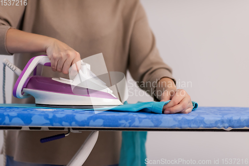 Image of Red haired woman ironing clothes at home