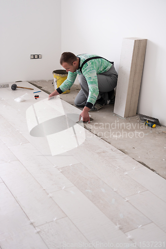 Image of worker installing the ceramic wood effect tiles on the floor