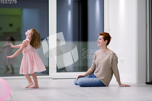 Image of mother and cute little daughter playing with balloons