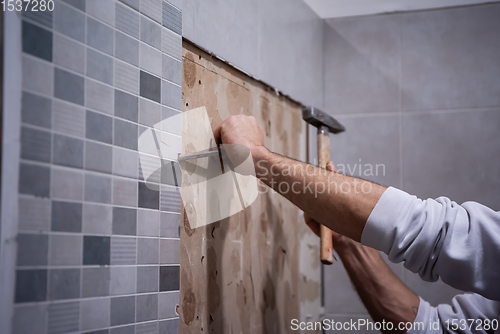 Image of worker remove demolish old tiles in a bathroom