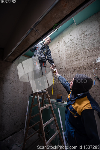 Image of construction workers installing roof window