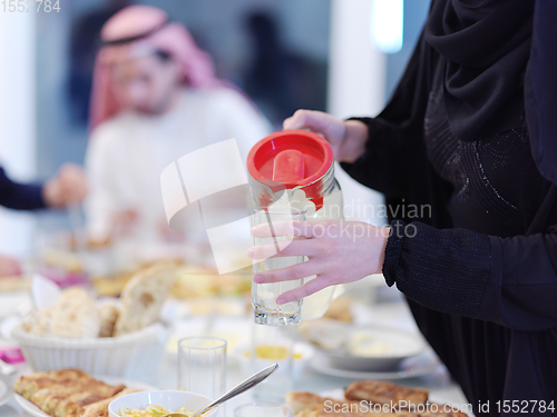 Image of Muslim family having Iftar dinner drinking water to break feast