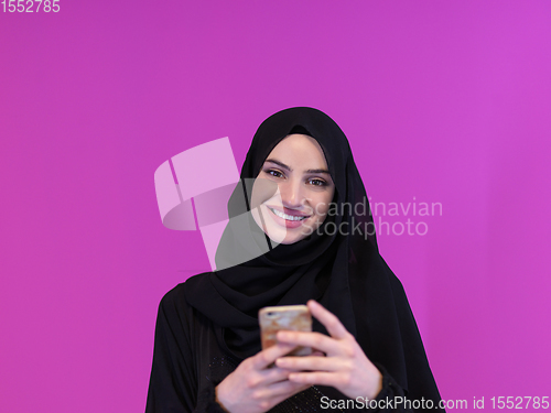 Image of muslim business woman using smartphone on pink background