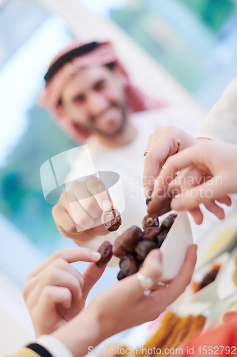 Image of Muslim family having Iftar dinner eating dates to break feast