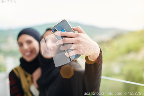 Image of muslim women taking selfie picture on the balcony