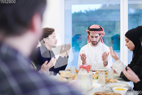 Image of traditional muslim family praying before iftar dinner