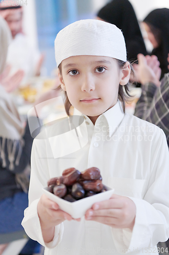 Image of little muslim boy holding a plate full of sweet dates