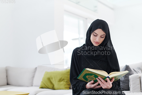 Image of young muslim woman reading Quran at home