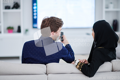 Image of young muslim couple watching TV together