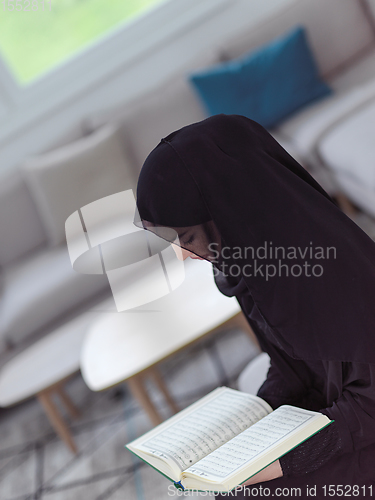 Image of young muslim woman reading Quran at home