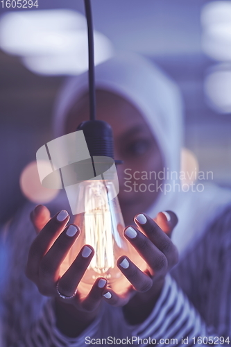 Image of internet of things concept woman holding hands around bulb