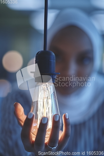 Image of internet of things concept woman holding hands around bulb