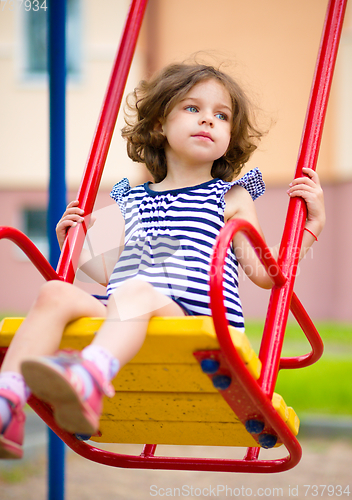 Image of Young happy girl is swinging in playground
