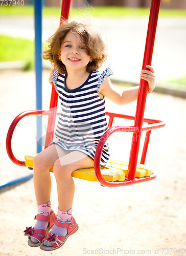 Image of Young happy girl is swinging in playground