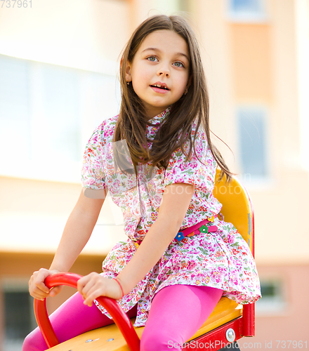 Image of Young happy girl is swinging in playground