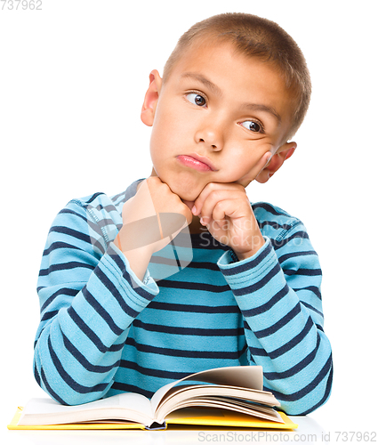 Image of Young boy is daydreaming while reading book