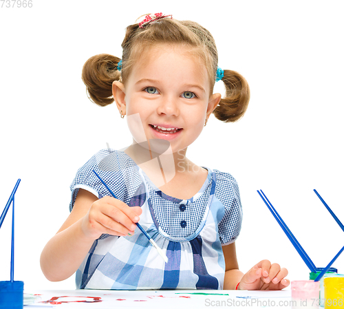 Image of Little girl is painting with gouache