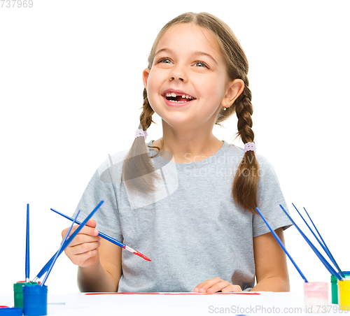 Image of Little girl is painting with gouache