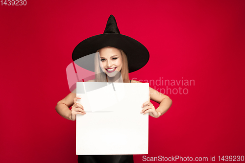 Image of Young woman in hat as a witch on red background