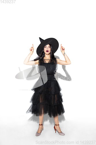 Image of Young woman in hat and dress as a witch on white background