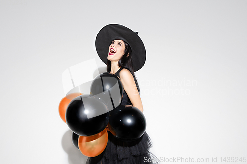 Image of Young woman in hat and dress as a witch on white background