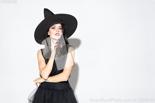 Image of Young woman in hat and dress as a witch on white background