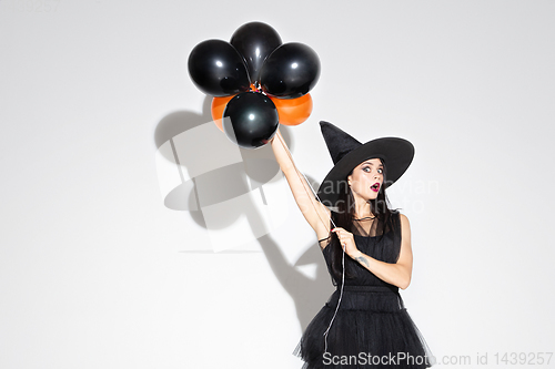 Image of Young woman in hat and dress as a witch on white background