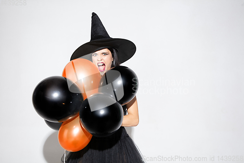 Image of Young woman in hat and dress as a witch on white background