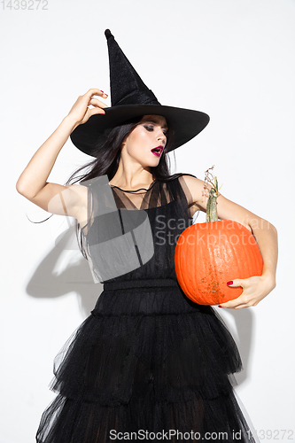 Image of Young woman in hat and dress as a witch on white background