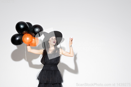 Image of Young woman in hat and dress as a witch on white background