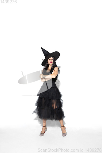 Image of Young woman in hat and dress as a witch on white background