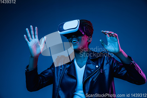 Image of Young african-american woman\'s using VR-glasses in neon light