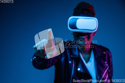 Image of Young african-american woman\'s using VR-glasses in neon light