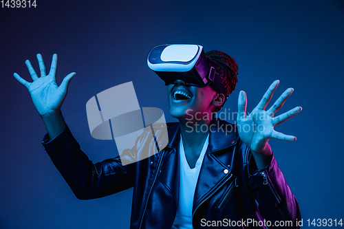 Image of Young african-american woman\'s using VR-glasses in neon light