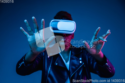 Image of Young african-american woman\'s using VR-glasses in neon light