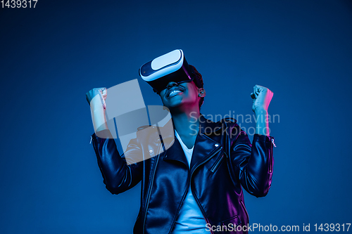 Image of Young african-american woman\'s using VR-glasses in neon light